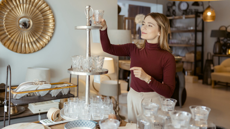 Woman looks at a glass while shopping in a store