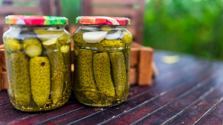 Two glass jars of homemade pickles sitting on a wooden table