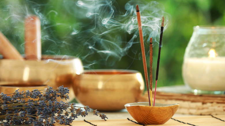 incense sticks burining next to dried lavender, singing bowls, and a candle