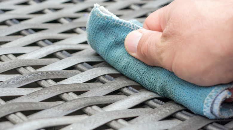 Person wiping wicker furniture with a cloth