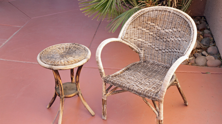 Older worn wicker chair and table set on a patio