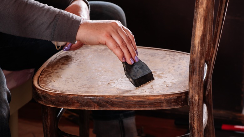 Person scraping vintage wood chair