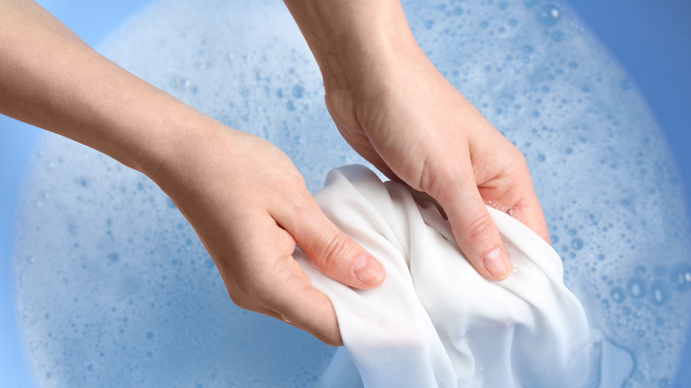 Hands soaking item in water