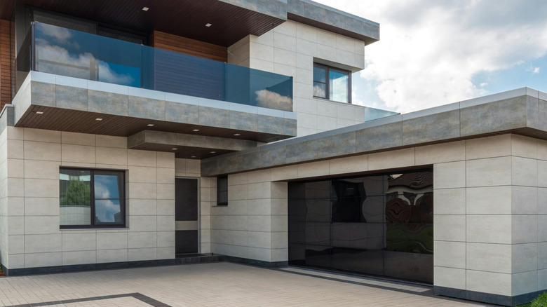 brutalist home built from stone, cement, and glass with a bare yard