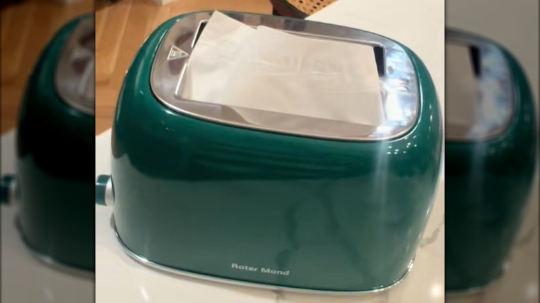 A mod green toaster that's broken is converted into a tissue dispenser
