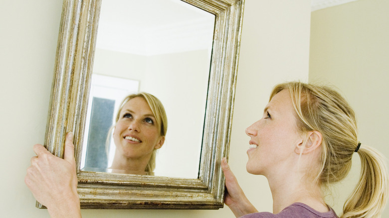 woman removing mirror from wall