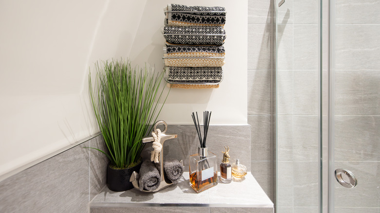 Nautical-themed bathroom decor including an anchor as a rolled towel holder, a reed diffuser and a plant