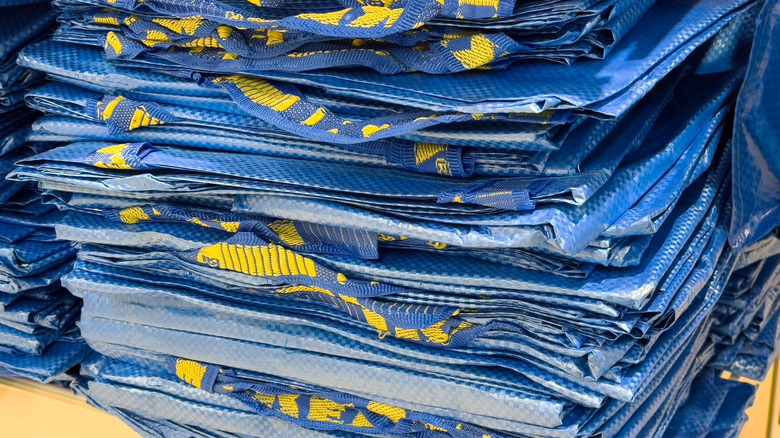 A tidy stack of flattened blue IKEA shopping bags sits neatly on a shelf