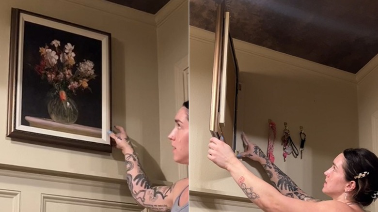 Person opening a frame to reveal keys hang behind the wall art