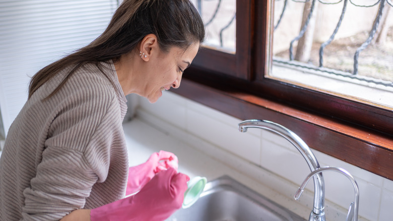 A woman trying to unclog her kitchen drain