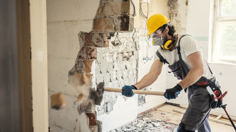 A person removing a wall with a sledgehammer