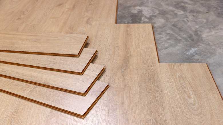 Luxury vinyl plank flooring made to look like wood being installed over stone floors