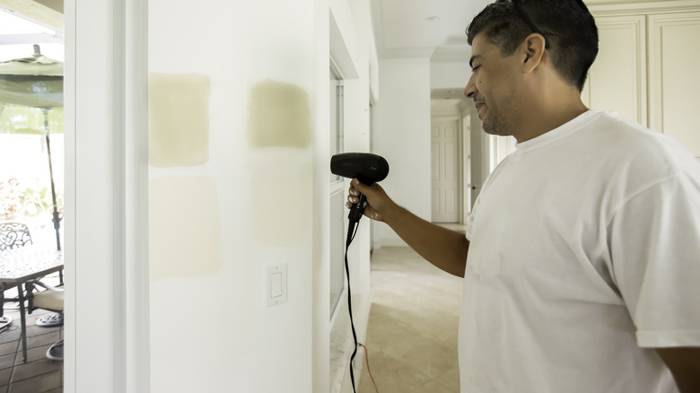 Man drying paint with hair dryer