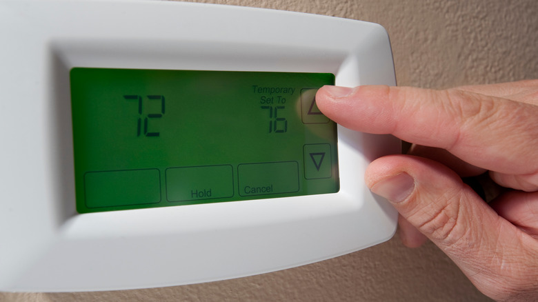 Hand changing the temperature on a digital thermostat