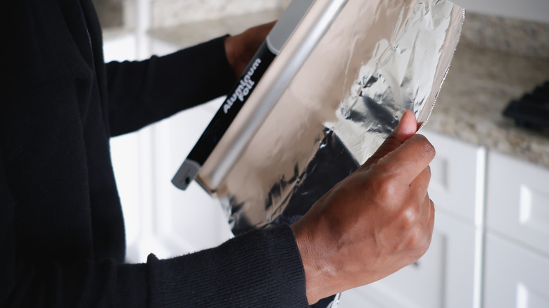 woman unrolling aluminum foil