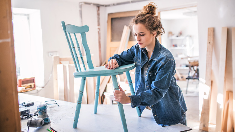 woman touching blue wooden chair 