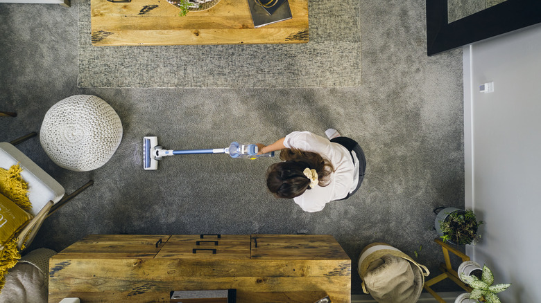 woman vacuuming gray carpet