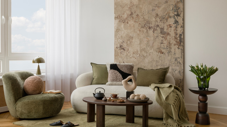 Neutral living room with various fabric textures and white and green furniture