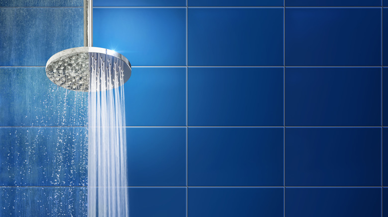 Blue shower tile wall and a steel shower head with running water