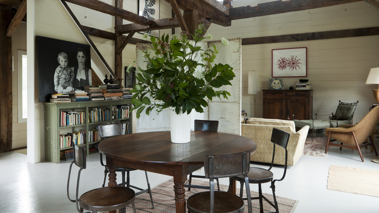 Open-plan dining and living area with wooden ceiling beams and rafters in converted barn