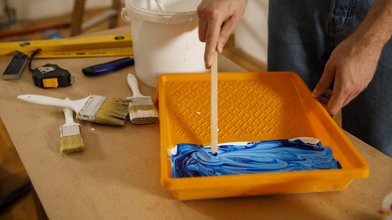 person mixing paint in tray