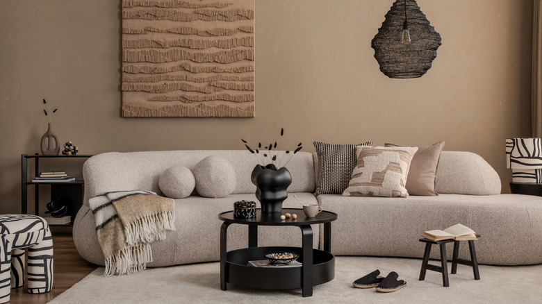 Curved off-white sofa with throw pillows amid coffee table and patterned side chairs