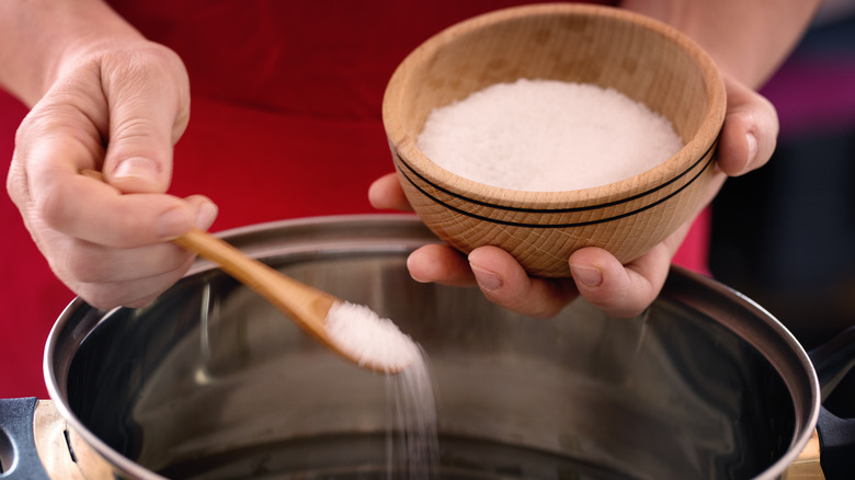 Pouring salt into bowl of water