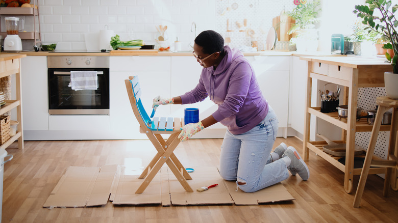 person painting chair in kitchen