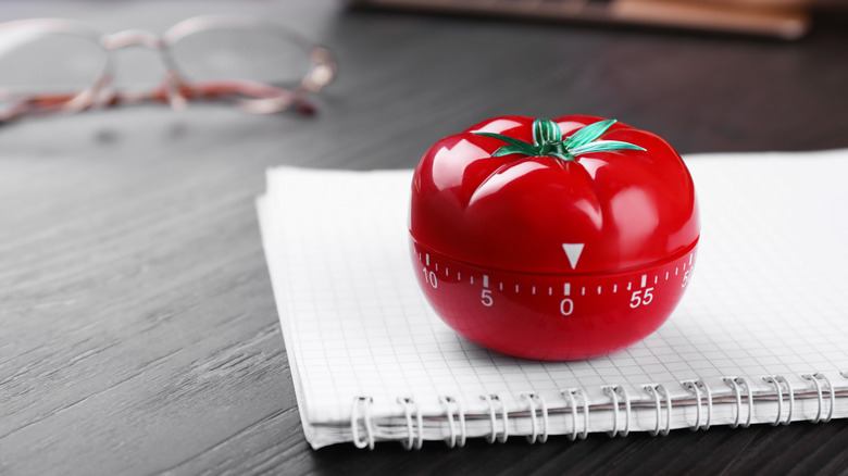 Tomato timer and notebook on a wooden table