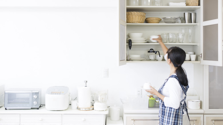 A woman putting dishes away in an organized kitchen