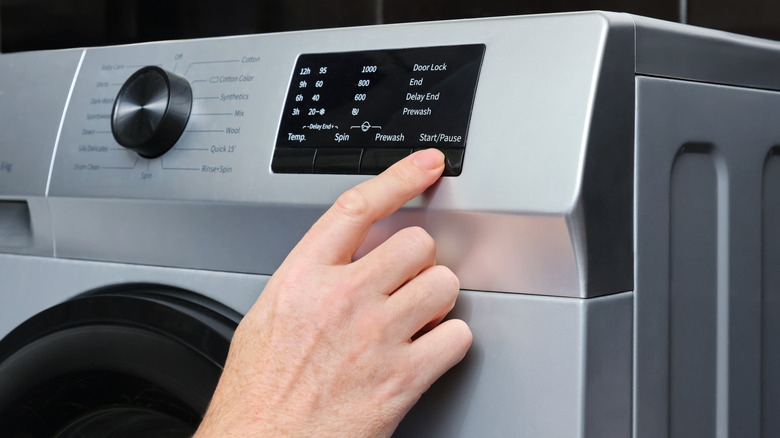 A man changes the wash setting on the washing machine panel.