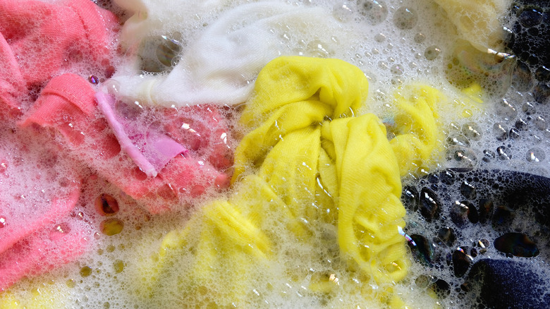 Clothes of different colors soaking in sudsy water.