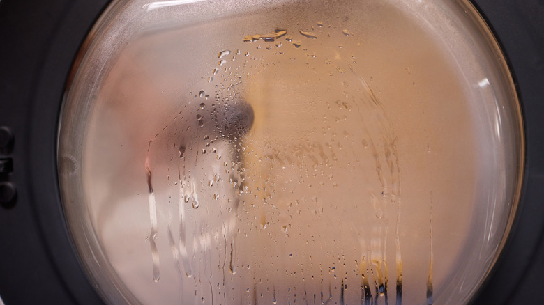 Steam and condensation on the window of a front-loading washing machine.