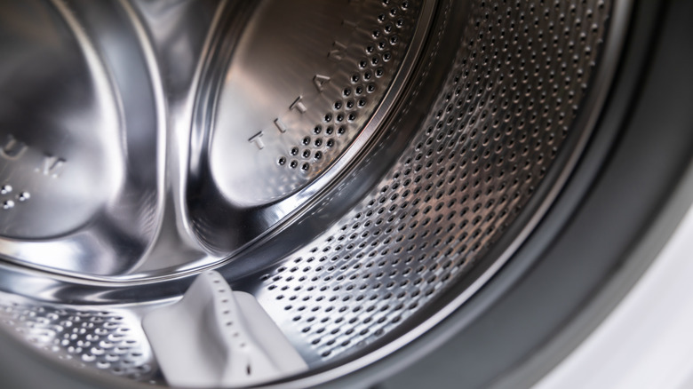 The silver metal inside of a front-loading washing machine drum.