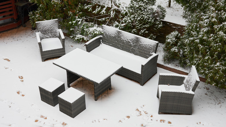 Woman standing inside her home, looking out of the window at her snowy patio.