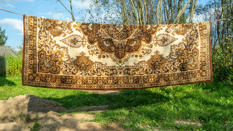A gold and white rug hanging on a clothes line
