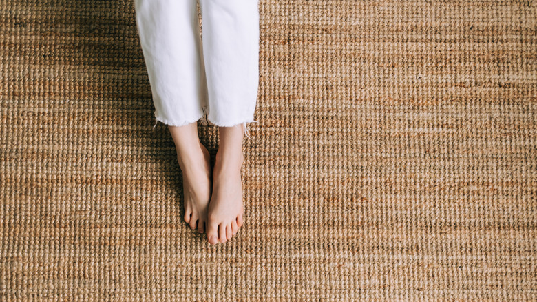 Person wearing white pants standing on a brown jute rug