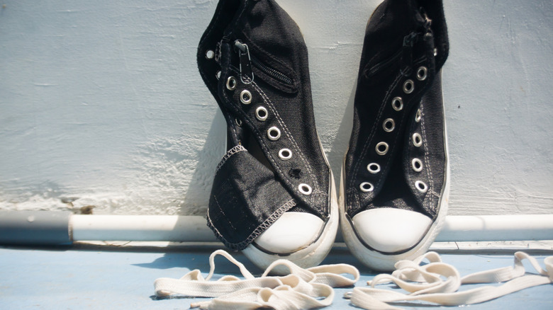 Black and white sneakers with the shoelaces removed, drying in the sun after being cleaned.