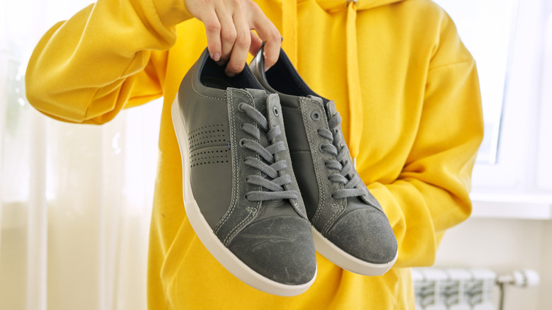 Someone holding a pair of grey sneakers