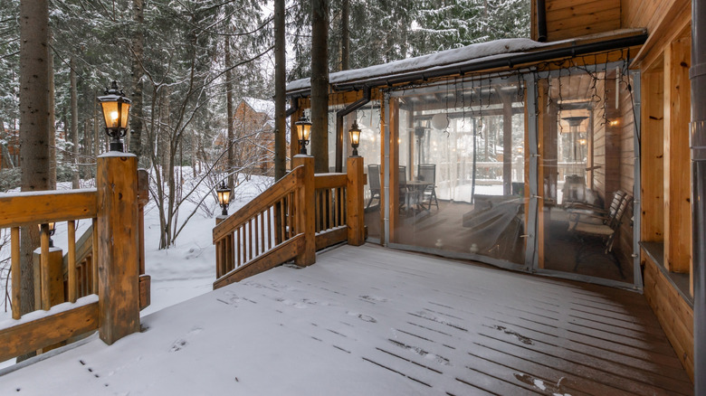 Cabin with wood deck covered in fresh white snow