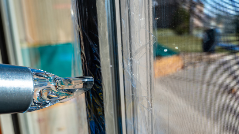 Someone winterizing a sliding glass door with thermal plastic coating