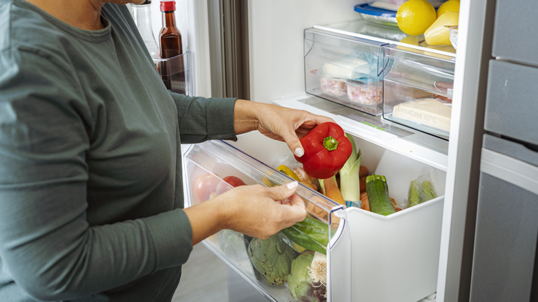 Woman putting red pepper in crisper drawer