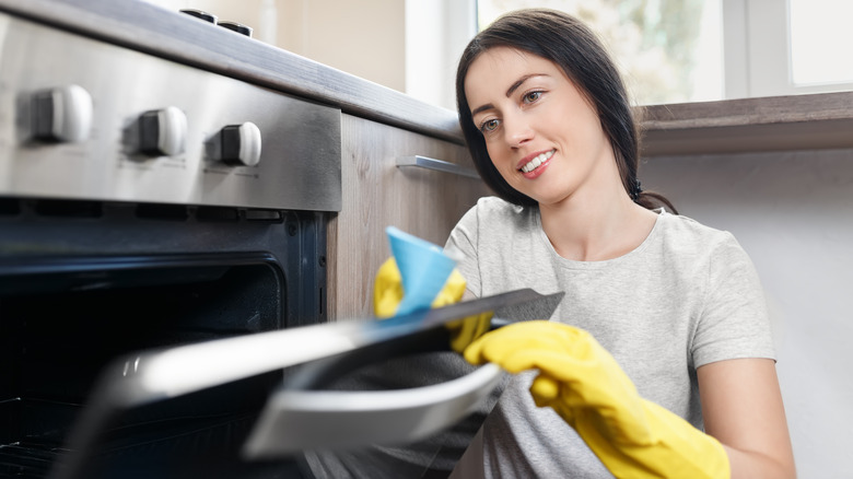 woman cleaning oven with rag