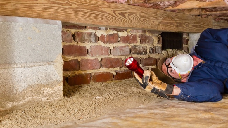 Man inspecting home's crawl space 