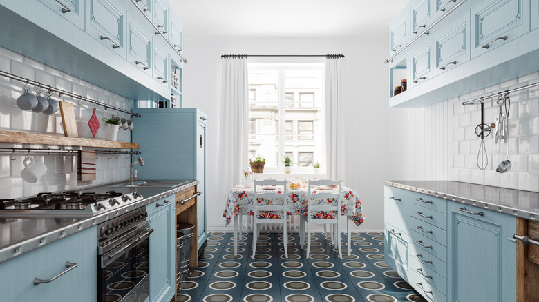 A light blue kitchen design with a dining table in front of a sunlit window