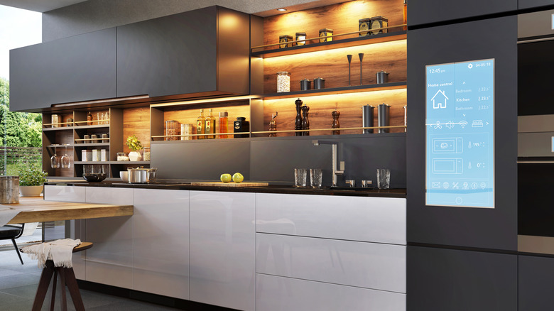 Gray and white kitchen cabinets with well-organized utensils and a smart screen for appliances control