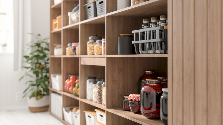 A wooden shelving system filled with various jars and containers of food and other kitchen items