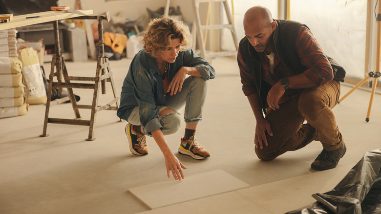 Two people crouched on the ground, looking at tile for a kitchen remodel