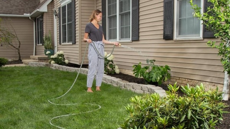 Woman using expandable garden hose to water plants