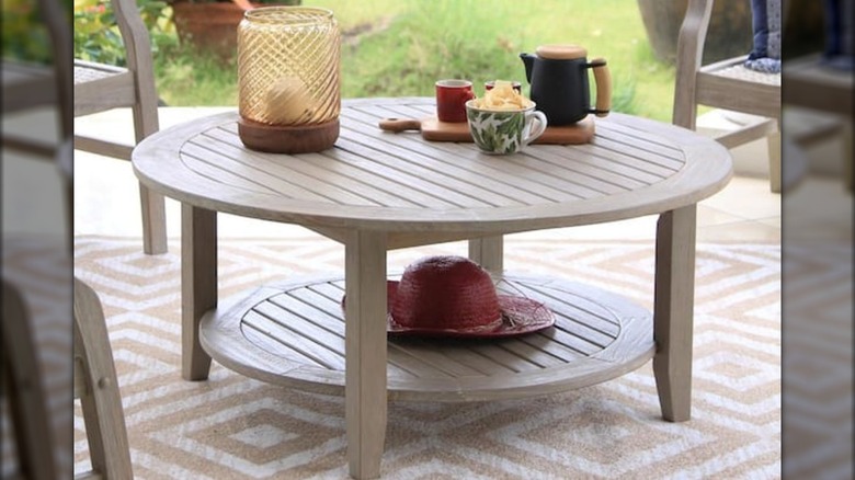 Round wooden outdoor coffee table on patio with decor